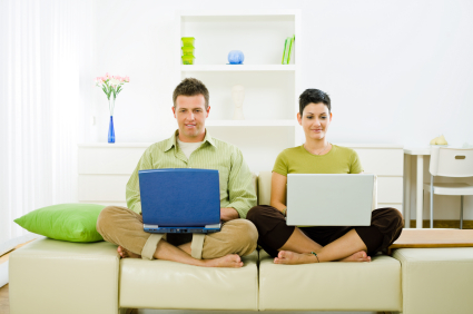 Young couple sitting on sofa, using laptops